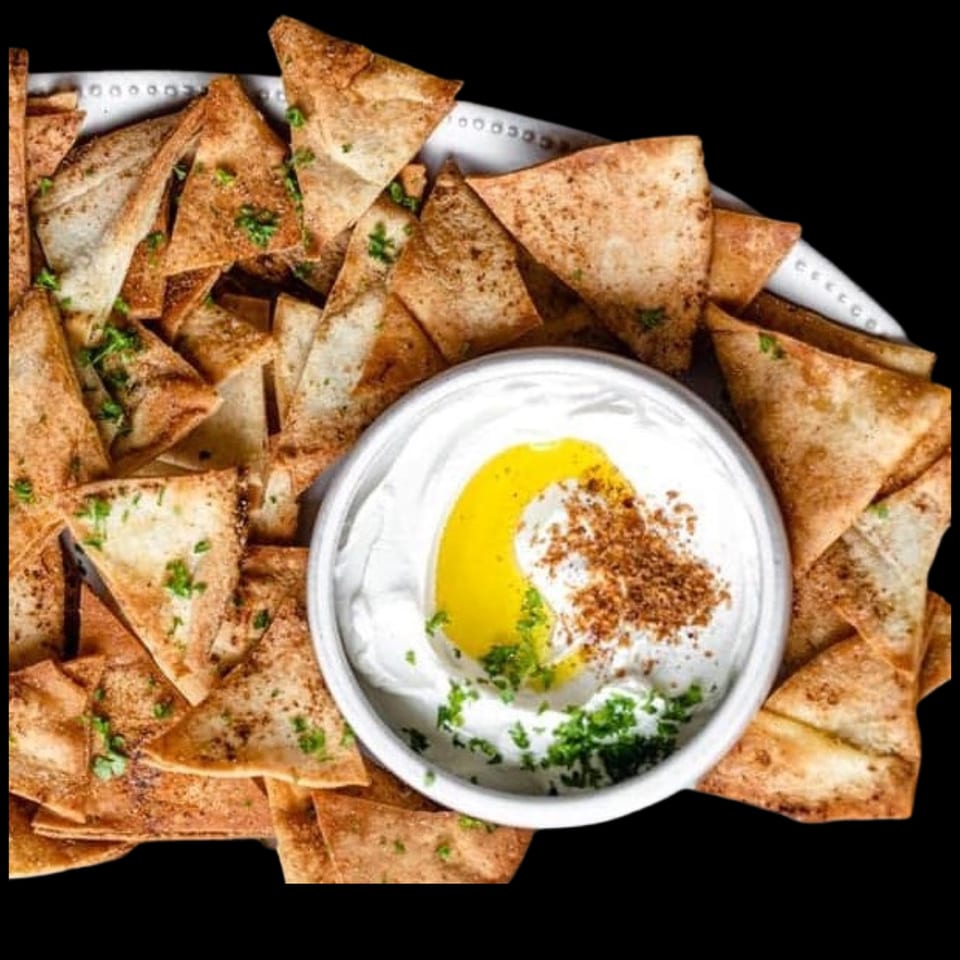 Crispy pita chips seasoned with herbs and spices, served with a creamy dip drizzled with olive oil.