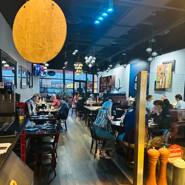 Diners enjoying meals inside Nora's Grill & Bistro, featuring Mediterranean decor and ambient lighting.