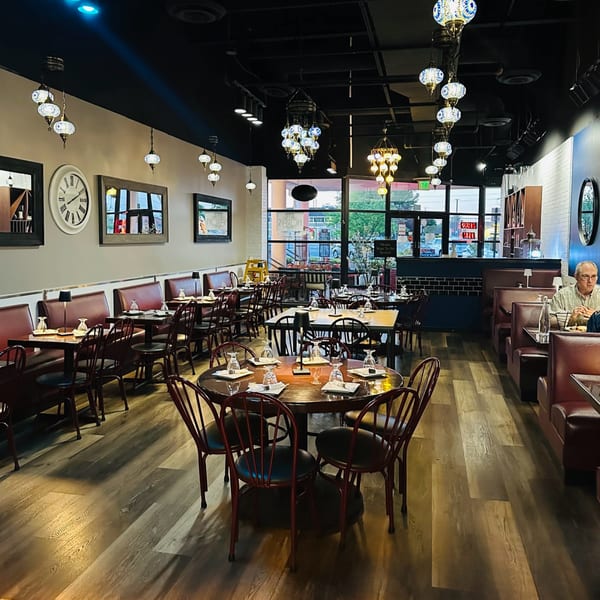 Nora's Grill & Bistro interior with tables, booths, and ornate Mediterranean-style hanging lamps.